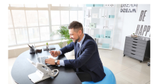 Exercising for Sedentary Lifestyles. Picture of a Caucasian male sitting on a ball in front of his desk.