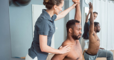 Physical Therapy in Pain Management. Picture of a young caucasian female physical therapist working with a young black male to guide his exercise treatment.