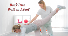 Back Pain: Wait and See Does Not Save Money. Picture of a young caucasian female on a mat with one leg stretched out, while a young caucasian female is working on her back.