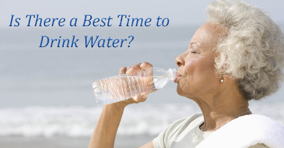 Timing Your Water Intake for Best Effects. Picture of an older black female drinking from a bottle of water, while along the shore line.